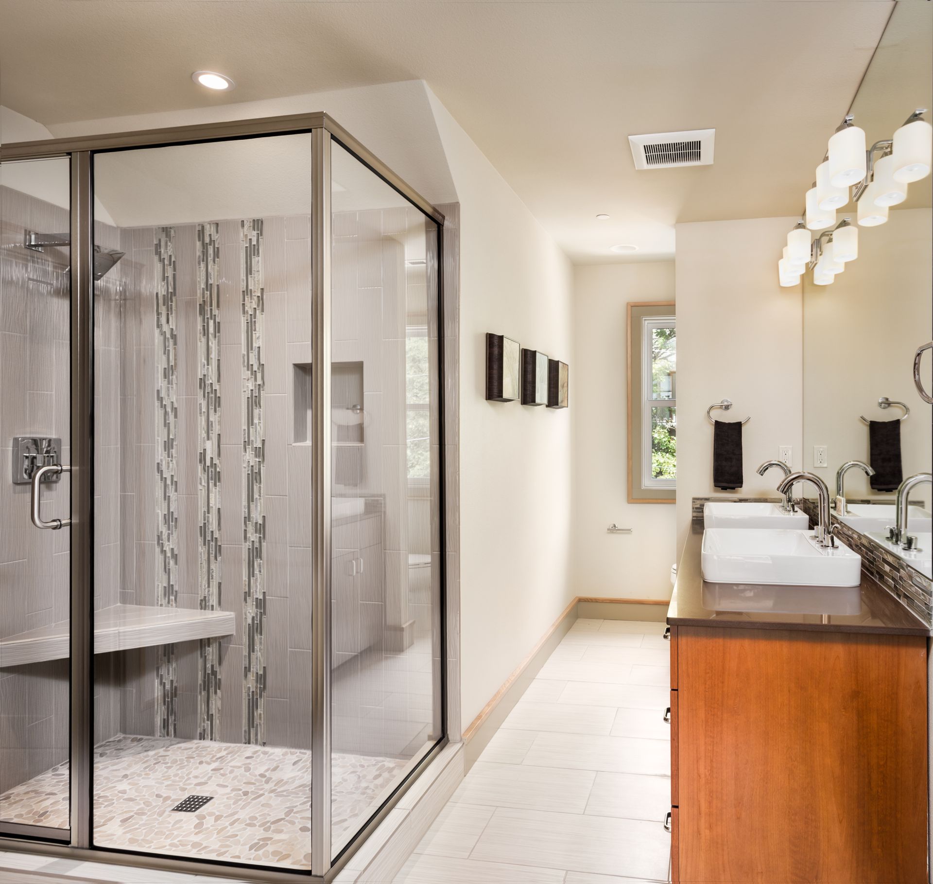 Modern bathroom with glass shower, double vanity, white tile, and wood cabinetry Modern bathroom with glass shower, double vanity, white tile, and wood cabinetry