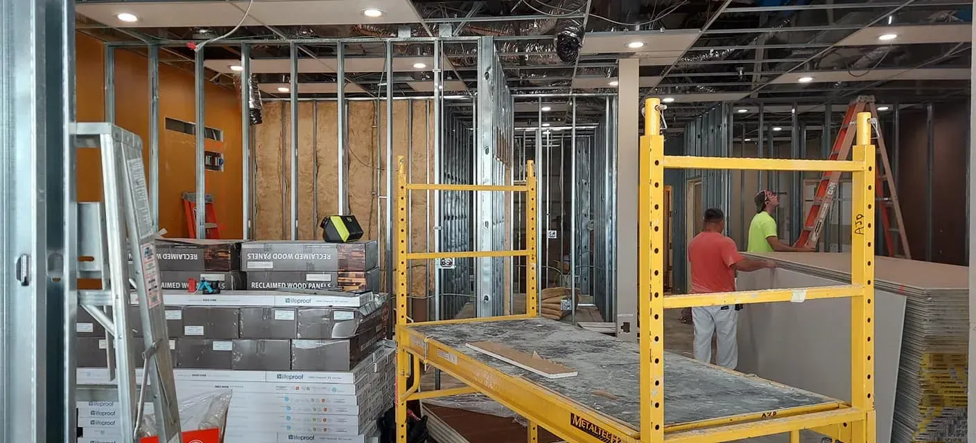 Construction site with workers on yellow scaffolding inside an unfinished building interior