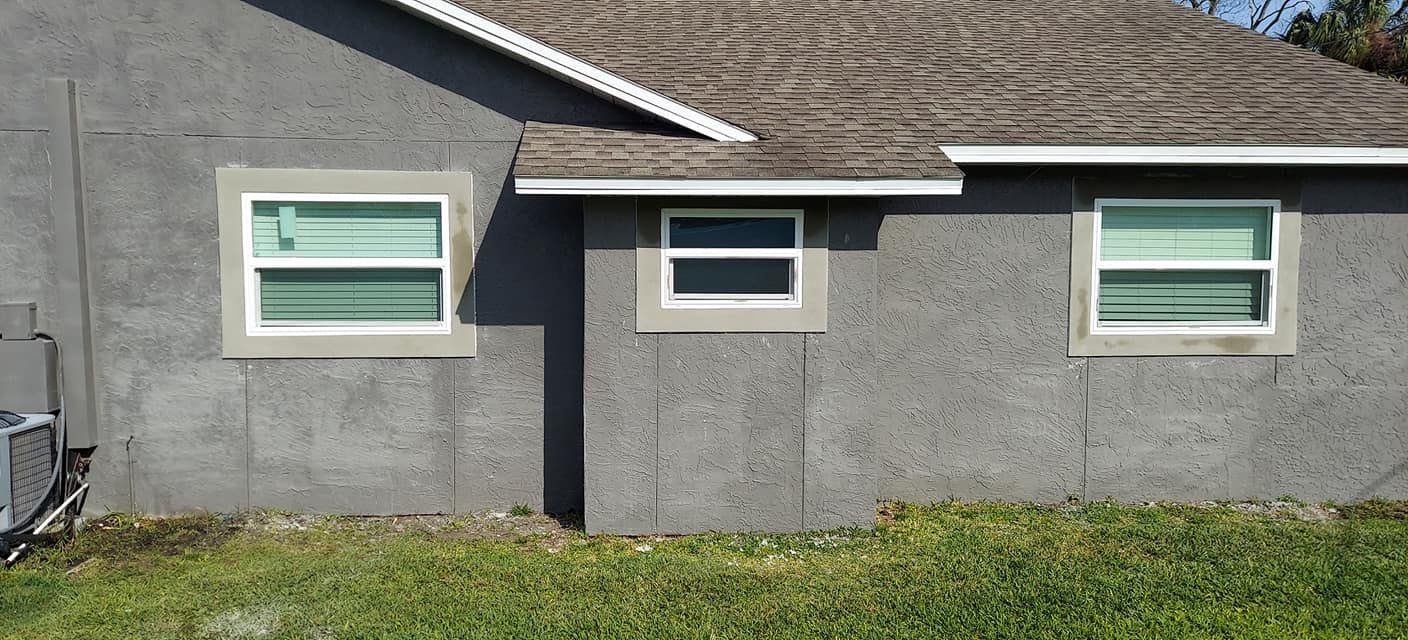 Gray house exterior with three windows and a small awning over the center window