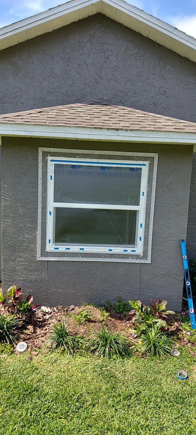Stucco house exterior with a single window, flower bed, and green lawn.