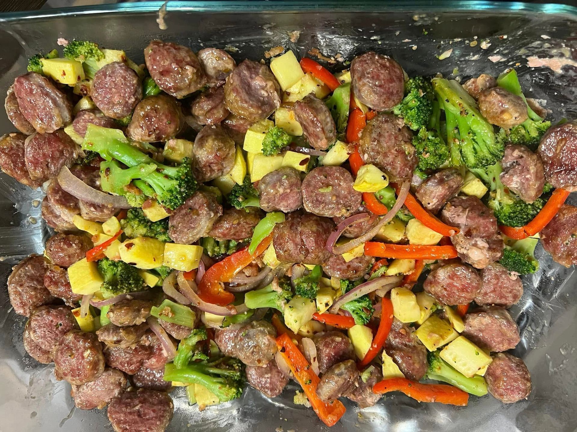 Baked sausage with broccoli, bell peppers, and potatoes in a roasting pan
