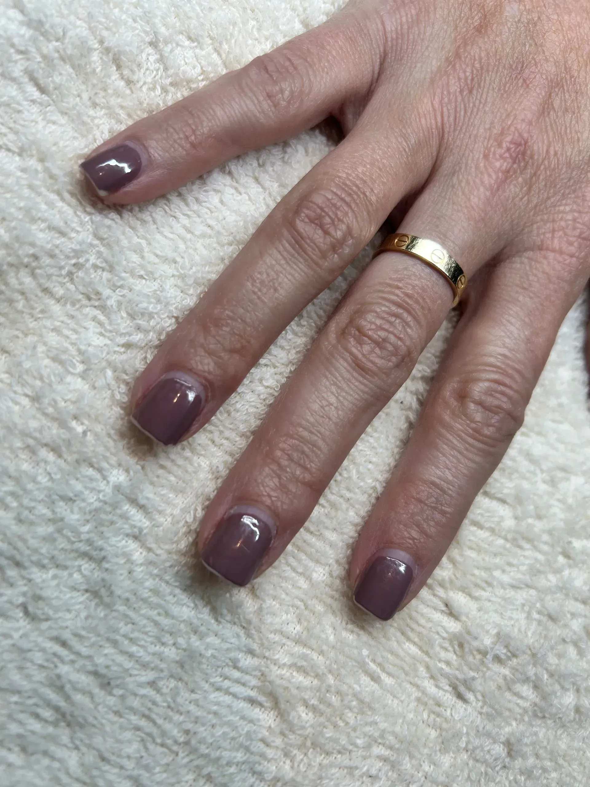 Hand with square-shaped, mauve-colored nail polish.