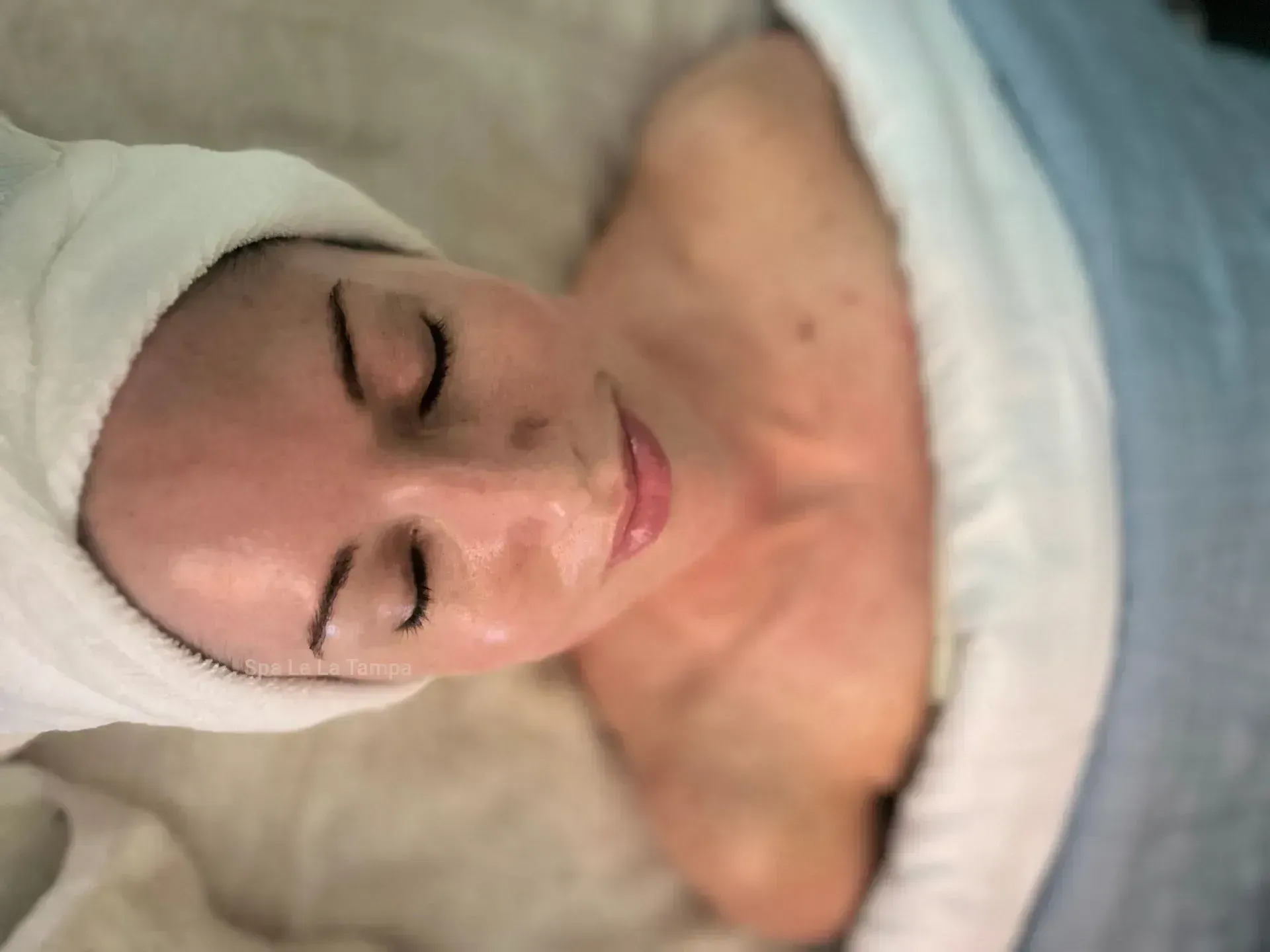 Woman with eyes closed, wrapped in a towel, receiving a facial. Woman with eyes closed, wrapped in a towel, receiving a facial.