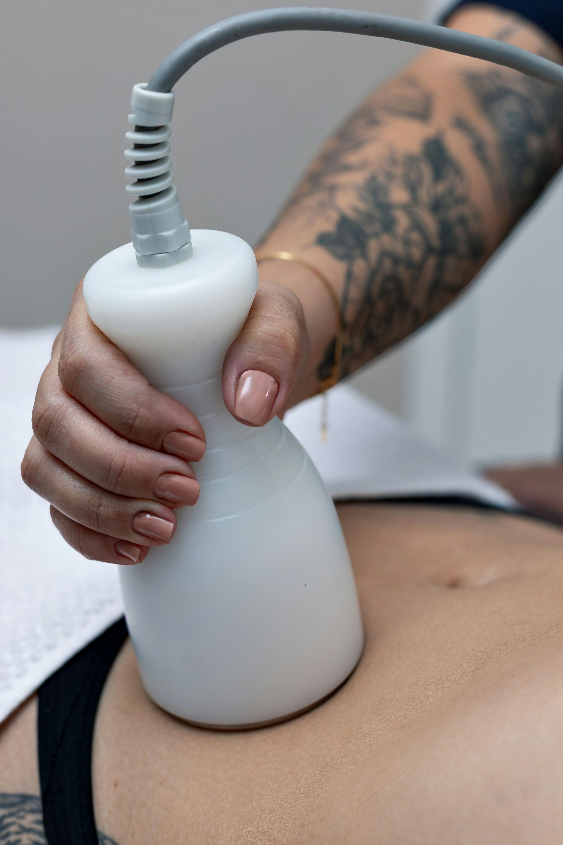 Hand holding a white ultrasound probe on a person’s abdomen during a scan