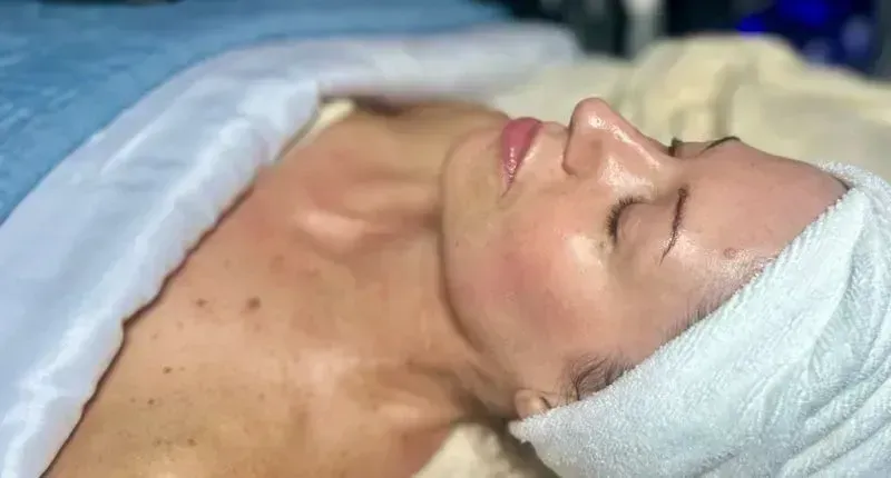 Woman with eyes closed, receiving a facial.