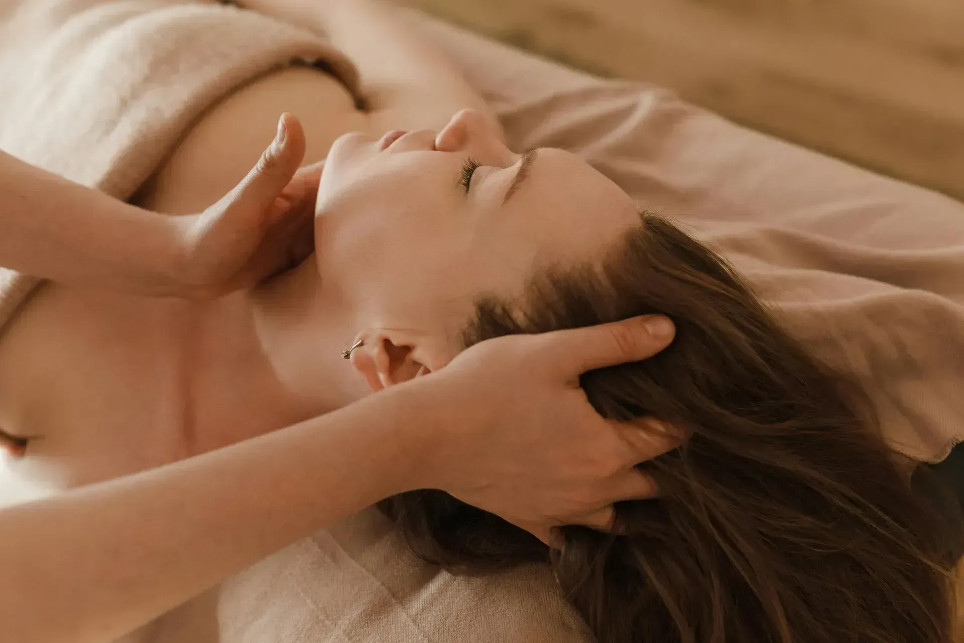 Person receiving a head massage on a massage table. Person receiving a head massage on a massage table.