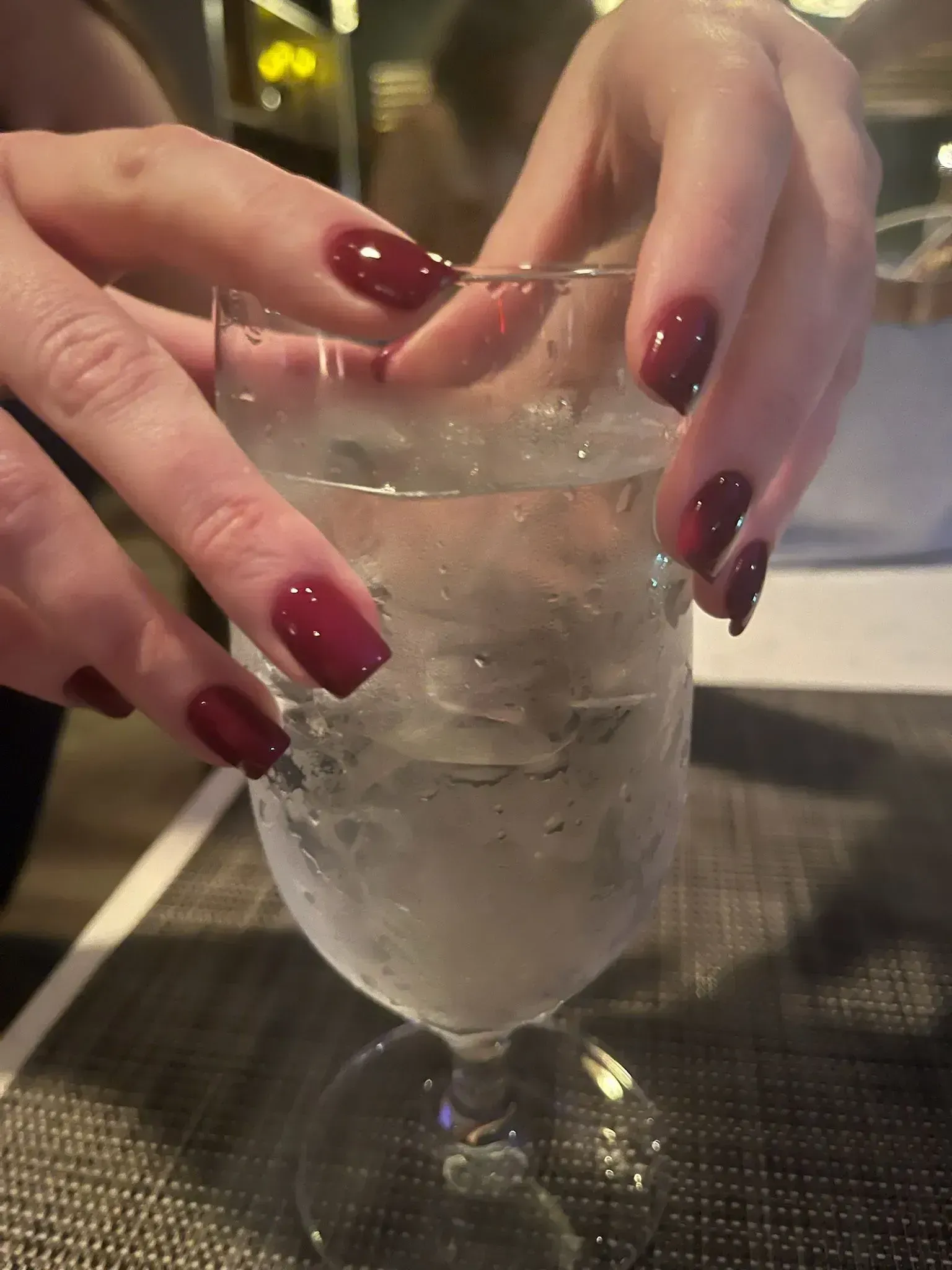 Hands with red nails holding a water-filled glass. Hands with red nails holding a water-filled glass.