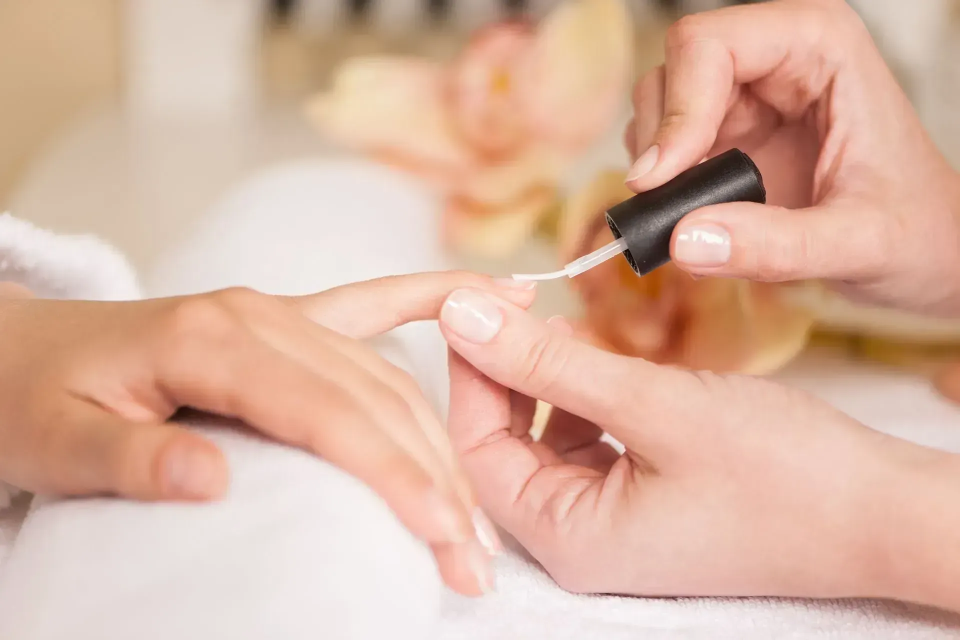 Manicurist applying clear nail polish to a client's fingernail at a salon. Manicurist applying clear nail polish to a client's fingernail at a salon.