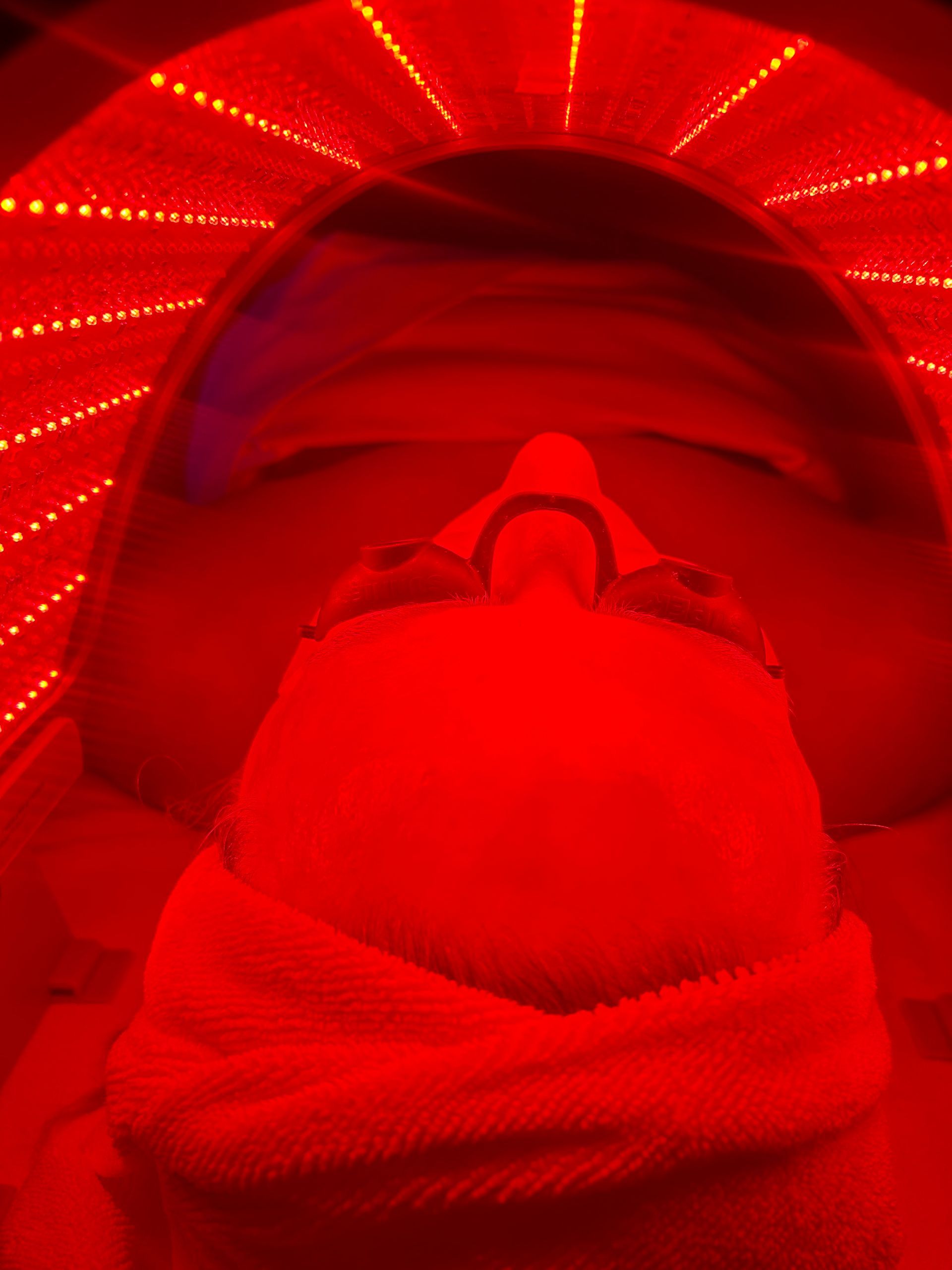 Close-up of a client receiving a red light therapy facial under an LED dome at Spa La La Tampa