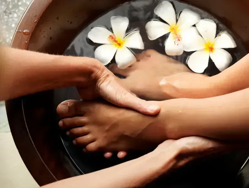 A woman's feet during a pedicure with candles and flowers
