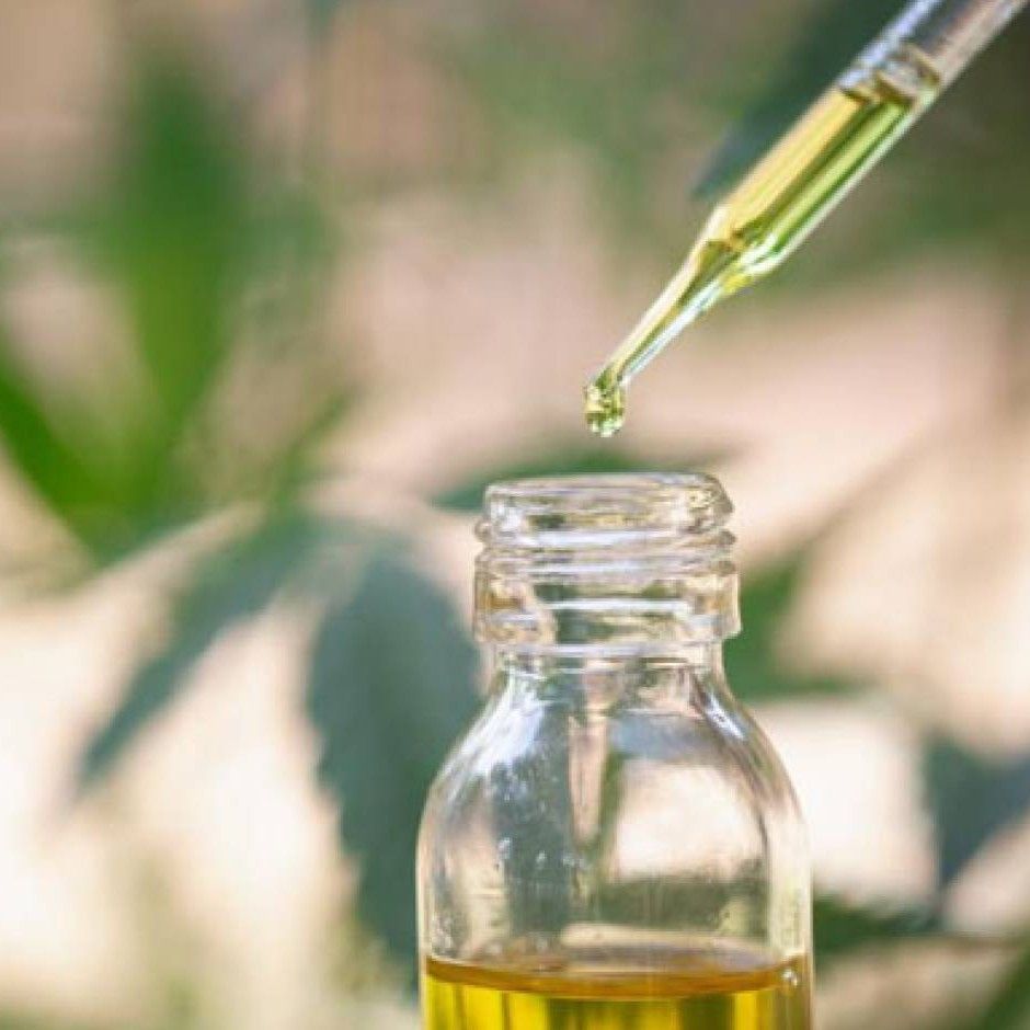 A drop of oil is being poured into a bottle with a pipette.