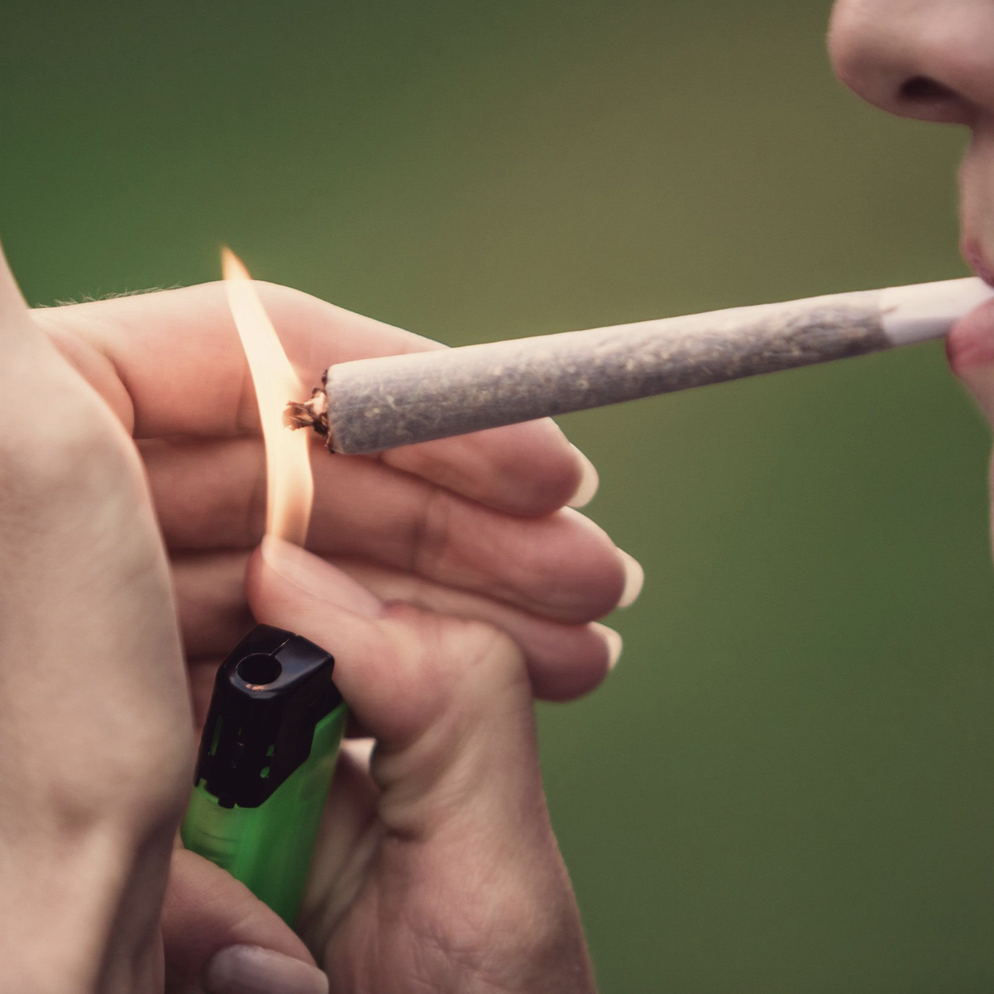 A person is using a lighter to start smoking a joint.