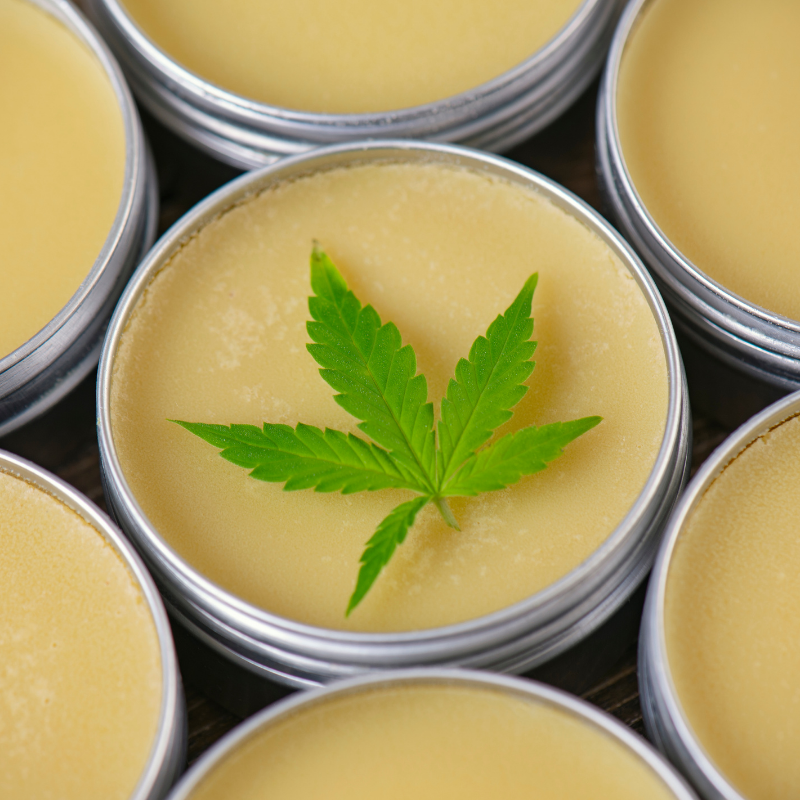 A cannabis Leaf resting on top of a cannabis infused topical