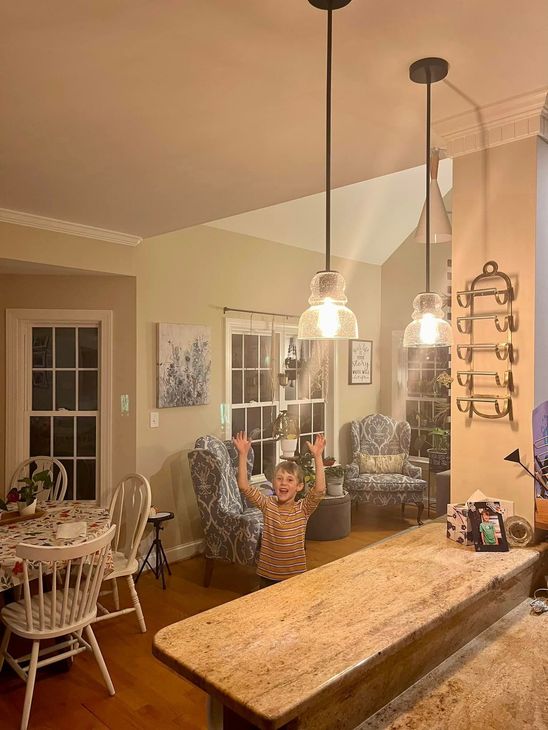 A little girl is standing in a living room next to a kitchen counter.