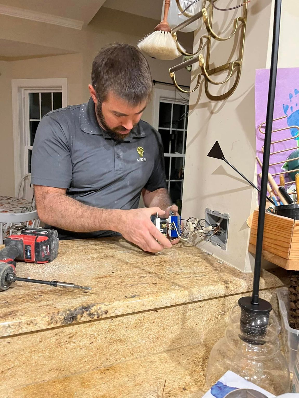 A man is sitting at a counter working on a light fixture.
