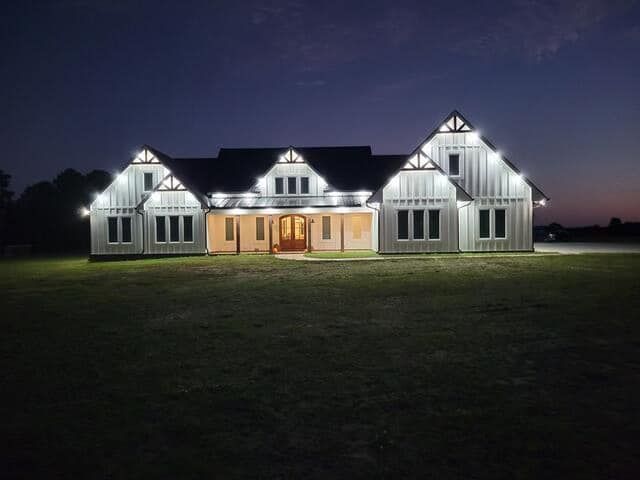 A large white house with a large porch and a white picket fence surrounding it.
