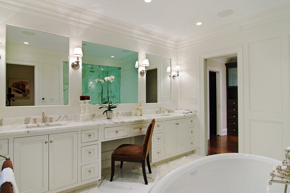 A bathroom with a tub , sinks , mirrors and a chair.