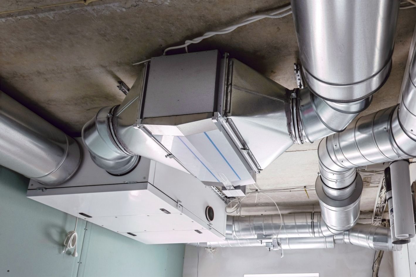 Système de ventilation comprenant des conduits métalliques montée sur un plafond.