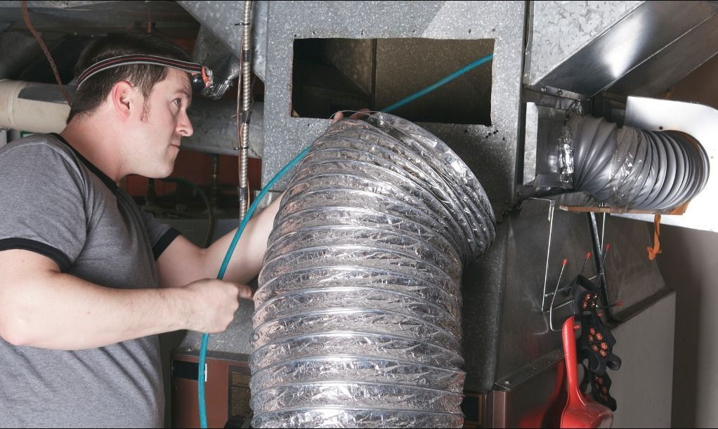 Un professionnel utilise un aspirateur pour nettoyer un conduit de ventilation.