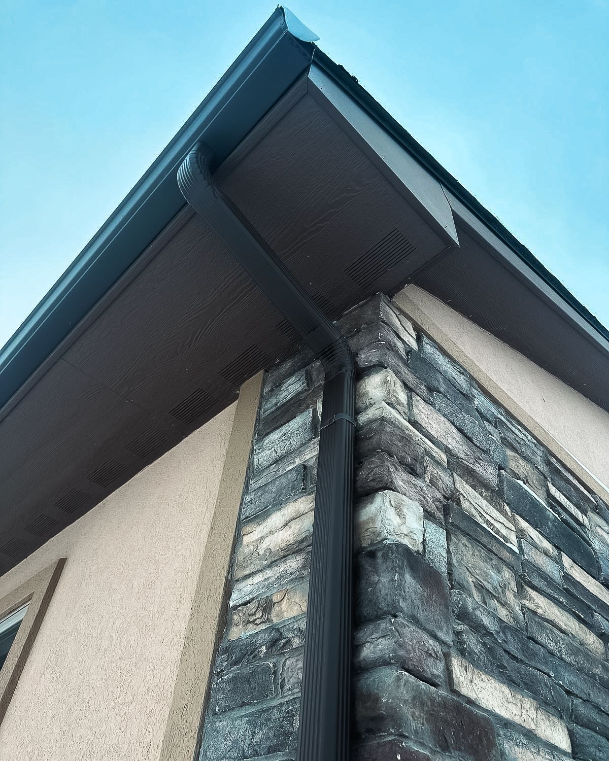 A house with a brick wall and a gutter on the side