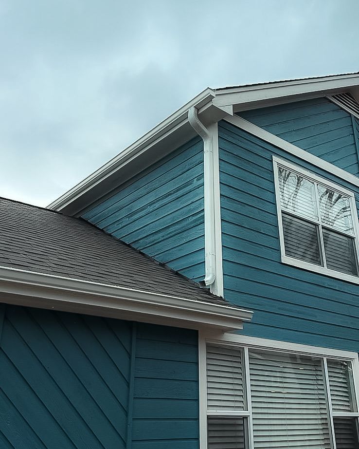 A blue house with a roof and a lot of windows