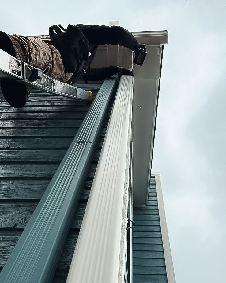 A man is standing on the roof of a building with a ladder.