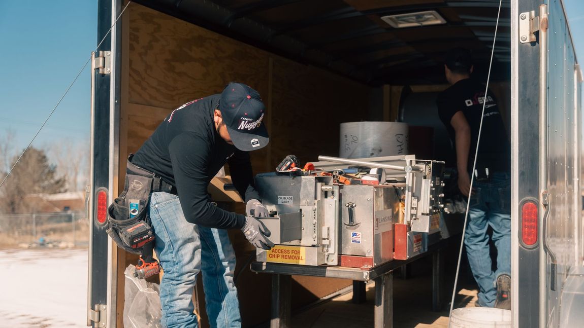 A man is working on a machine in the back of a trailer.