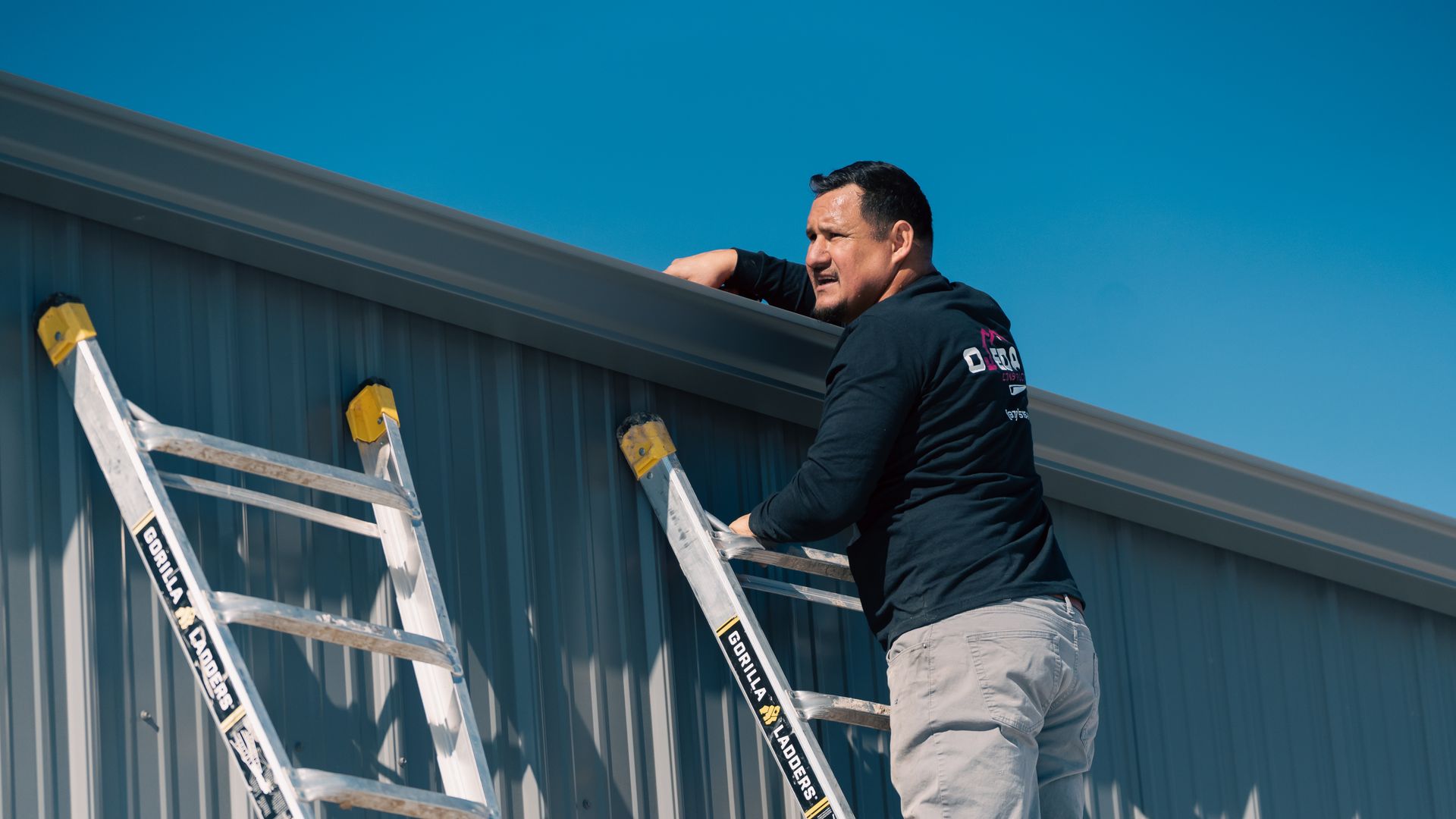 A man is standing on a ladder on the side of a building.