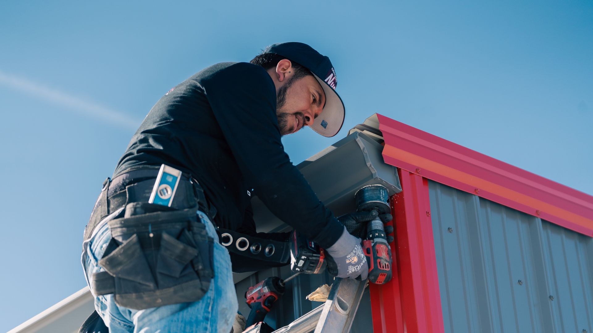 A man is working on the side of a building with a drill.
