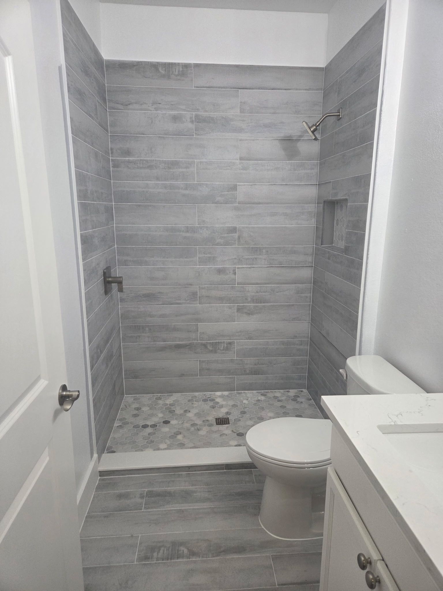 Small tiled bathroom under renovation with shower area, toilet, and vanity.