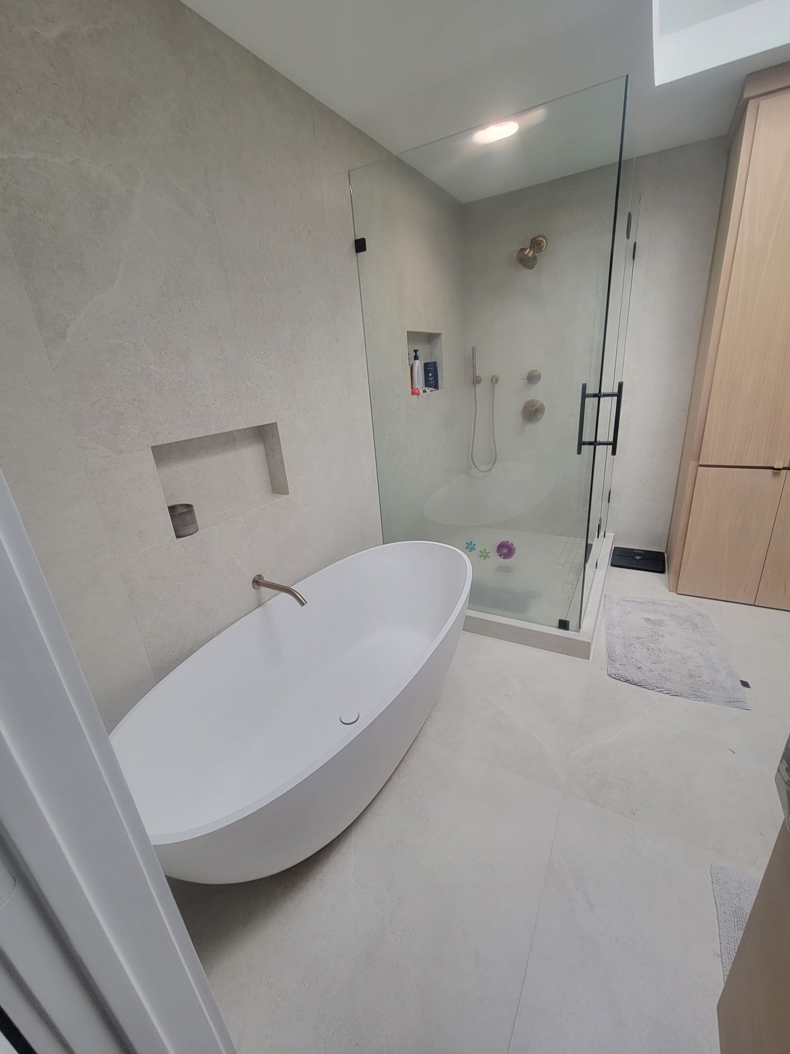 Modern bathroom with freestanding tub, glass shower, and light gray walls