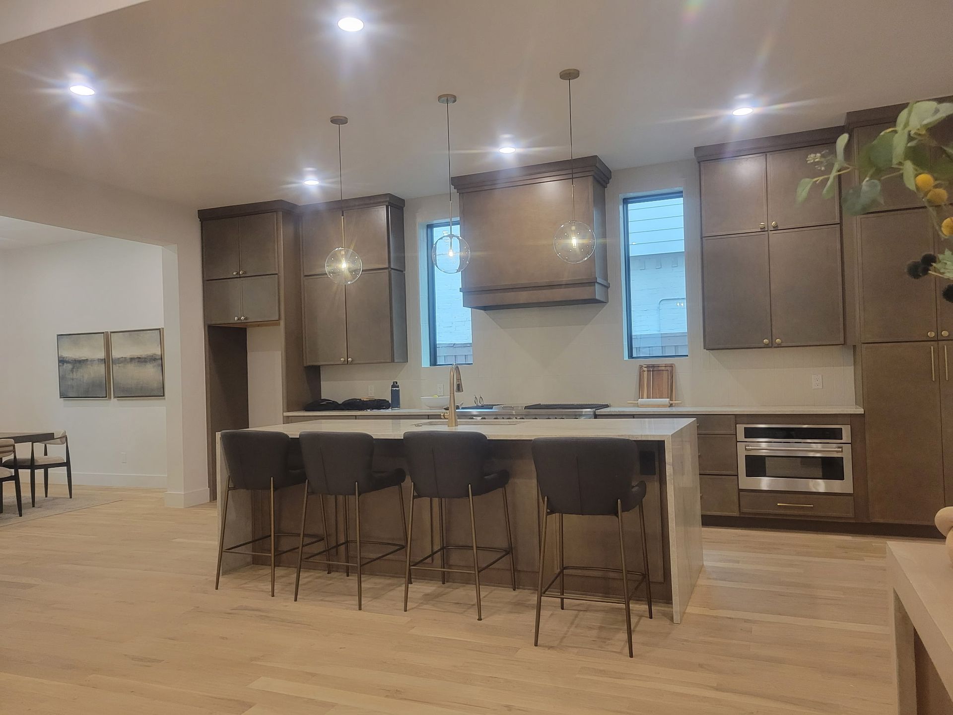 Modern kitchen with island, dark cabinets, bar stools, and pendant lights under a vaulted ceiling