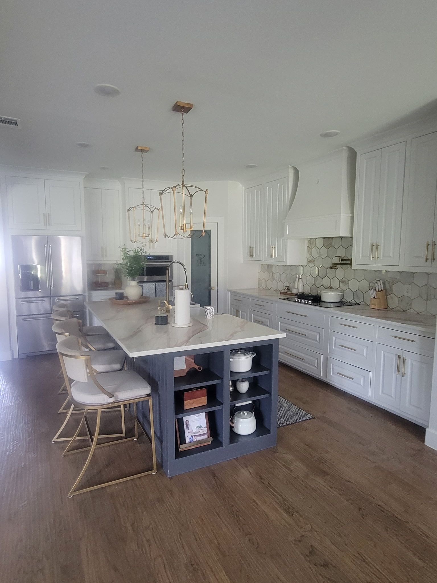 Bright white kitchen with island, bar stools, pendant lights, and hardwood floors
