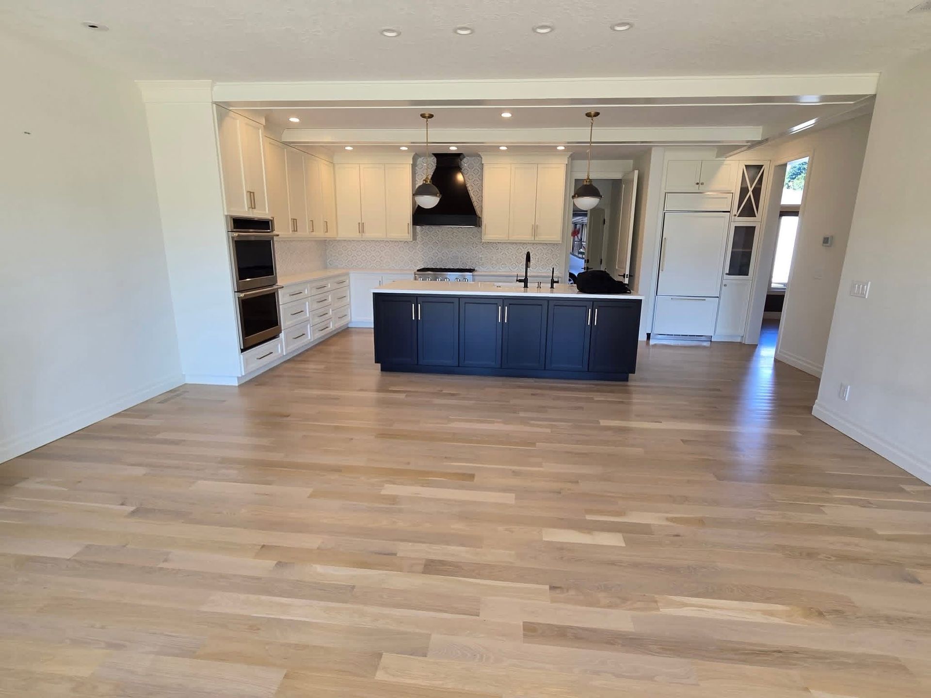 Bright open kitchen with white cabinets, dark island, and light wood floors in a modern room
