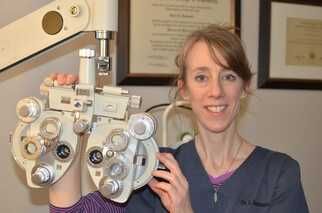 A woman is holding an eye examination machine in her hands.