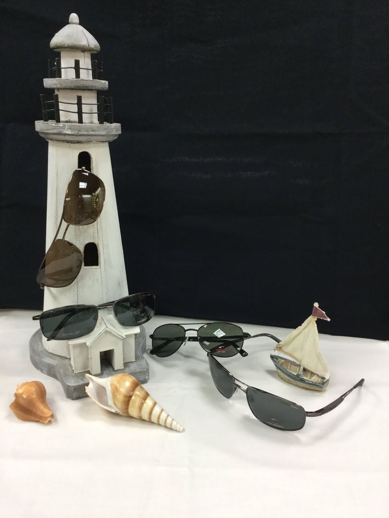A lighthouse , seashells , sunglasses and a sailboat are on a table.
