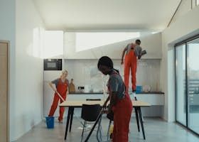 Hand holding a red paint roller applying white paint to a gray wall