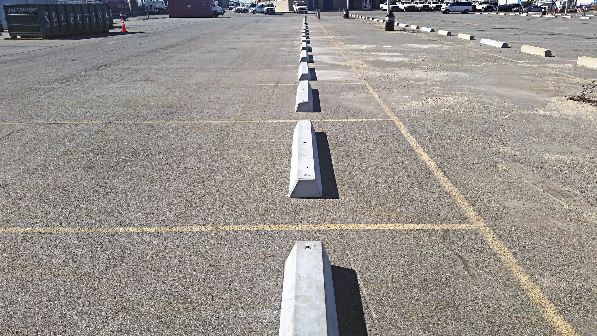 Parking lot with concrete parking stops, marked spaces.