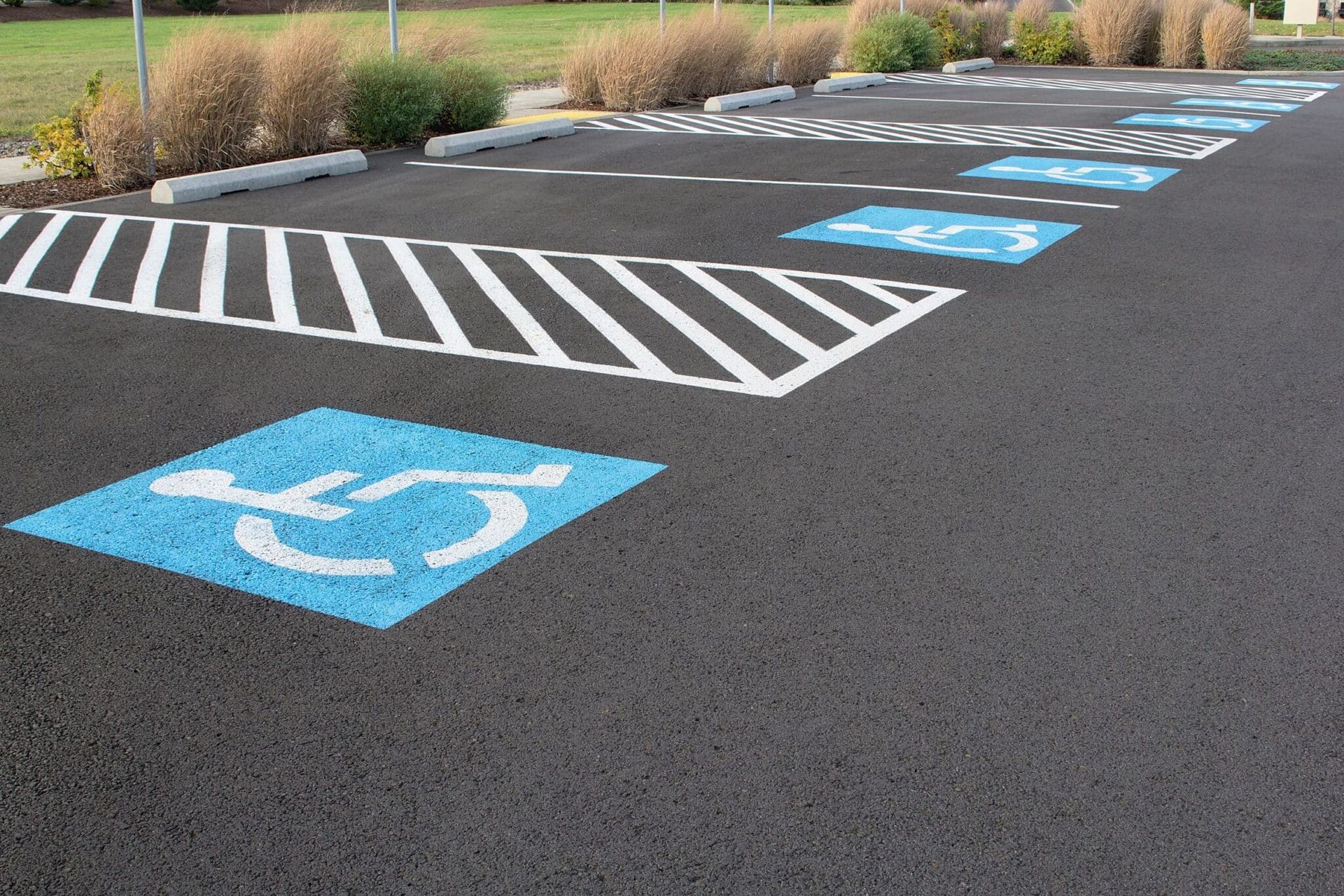 Parking lot with blue handicap symbols and white striped crosshatch markings.