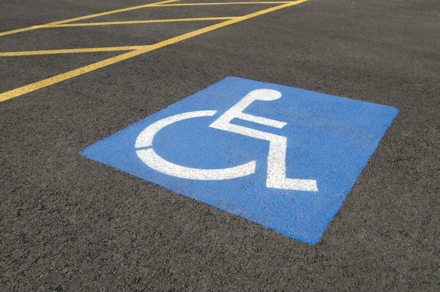 Blue and white handicap symbol painted on asphalt in a parking space.