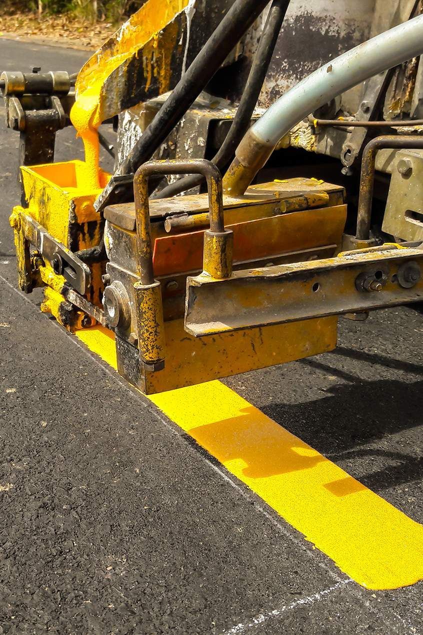 Yellow paint being applied by a machine to create a road marking.