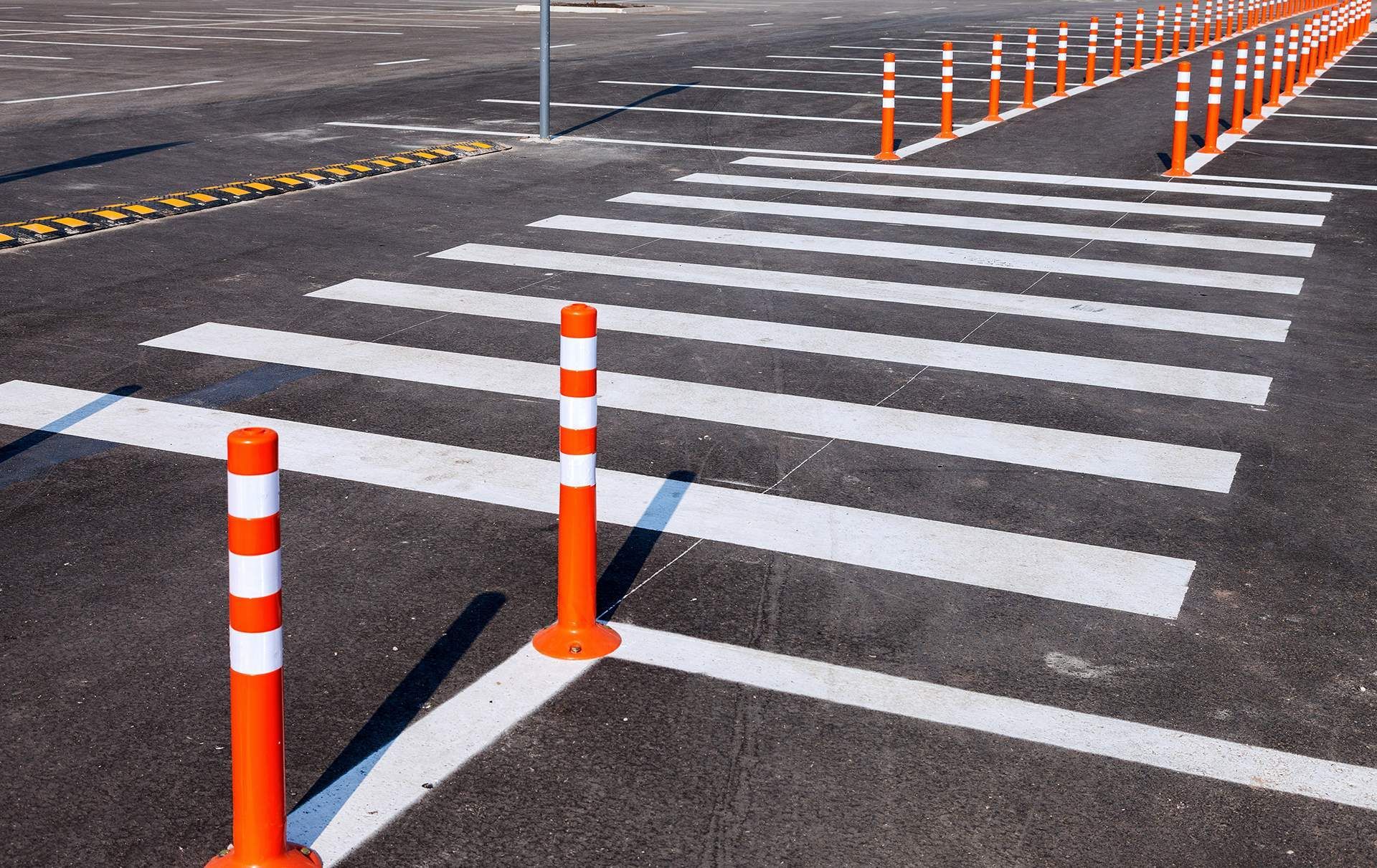 Crosswalk with orange and white bollards on asphalt.