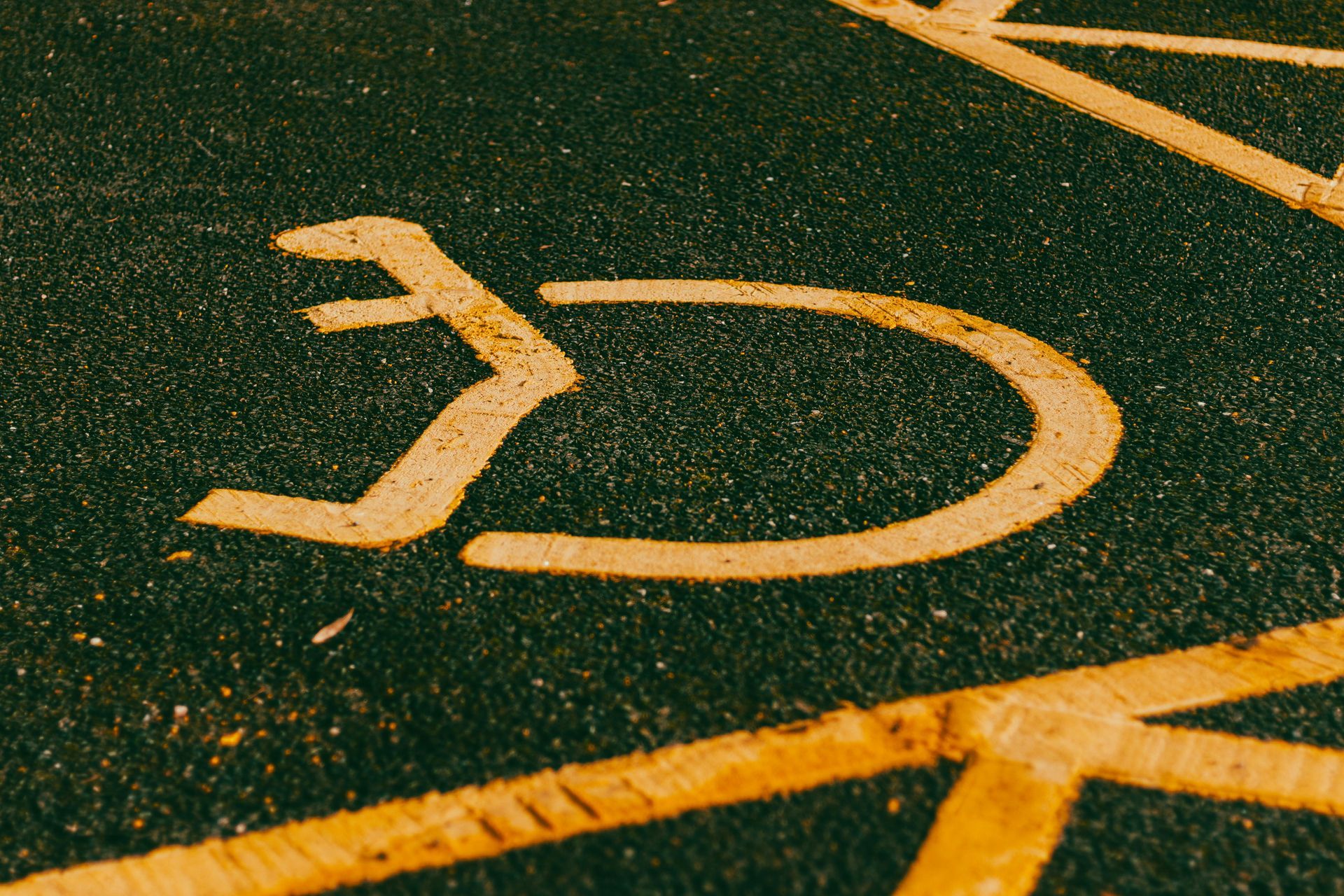 Yellow handicap symbol painted on dark asphalt.