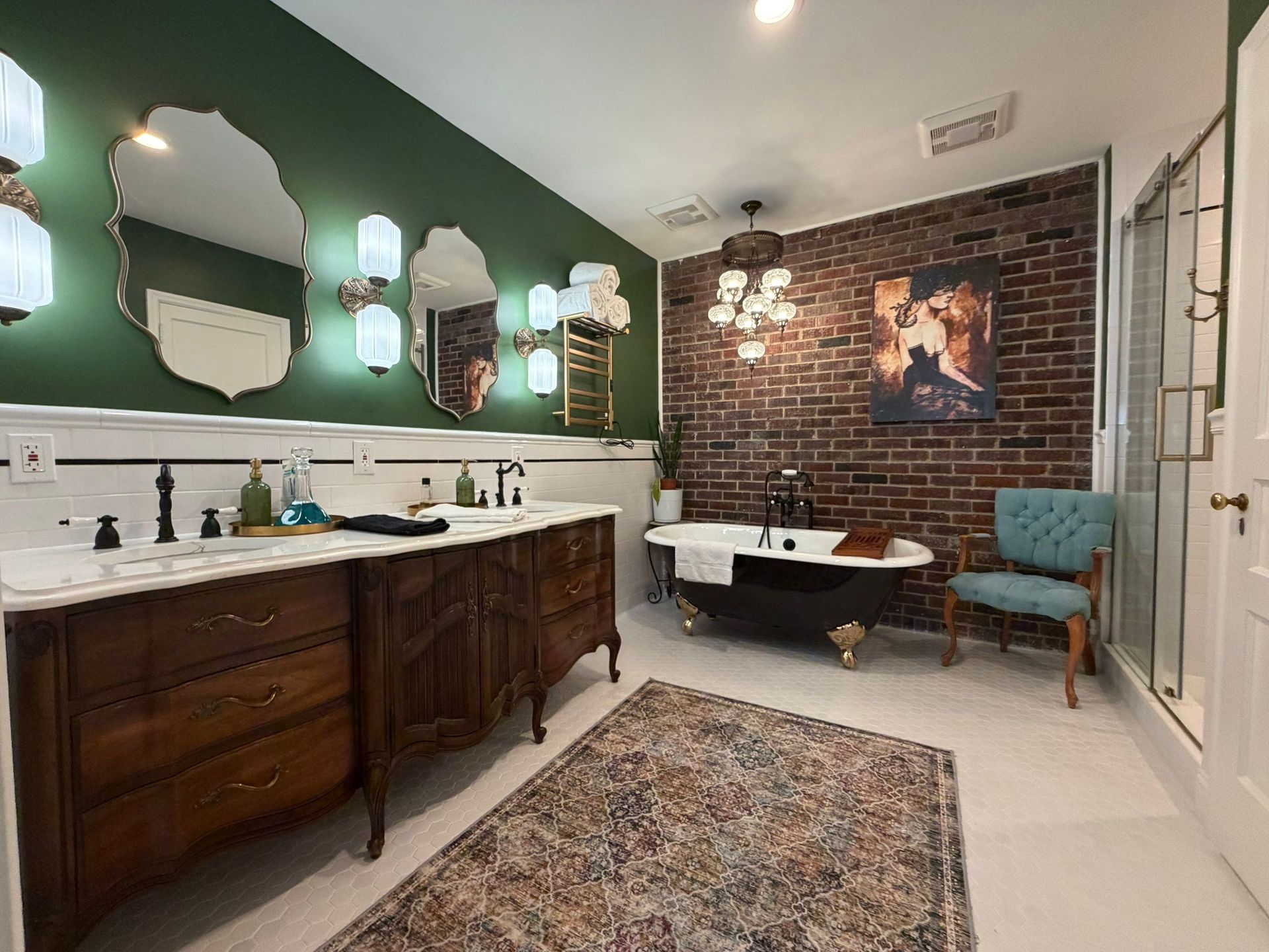 Elegant bathroom with double vanity, green walls, brick accent wall, and freestanding tub