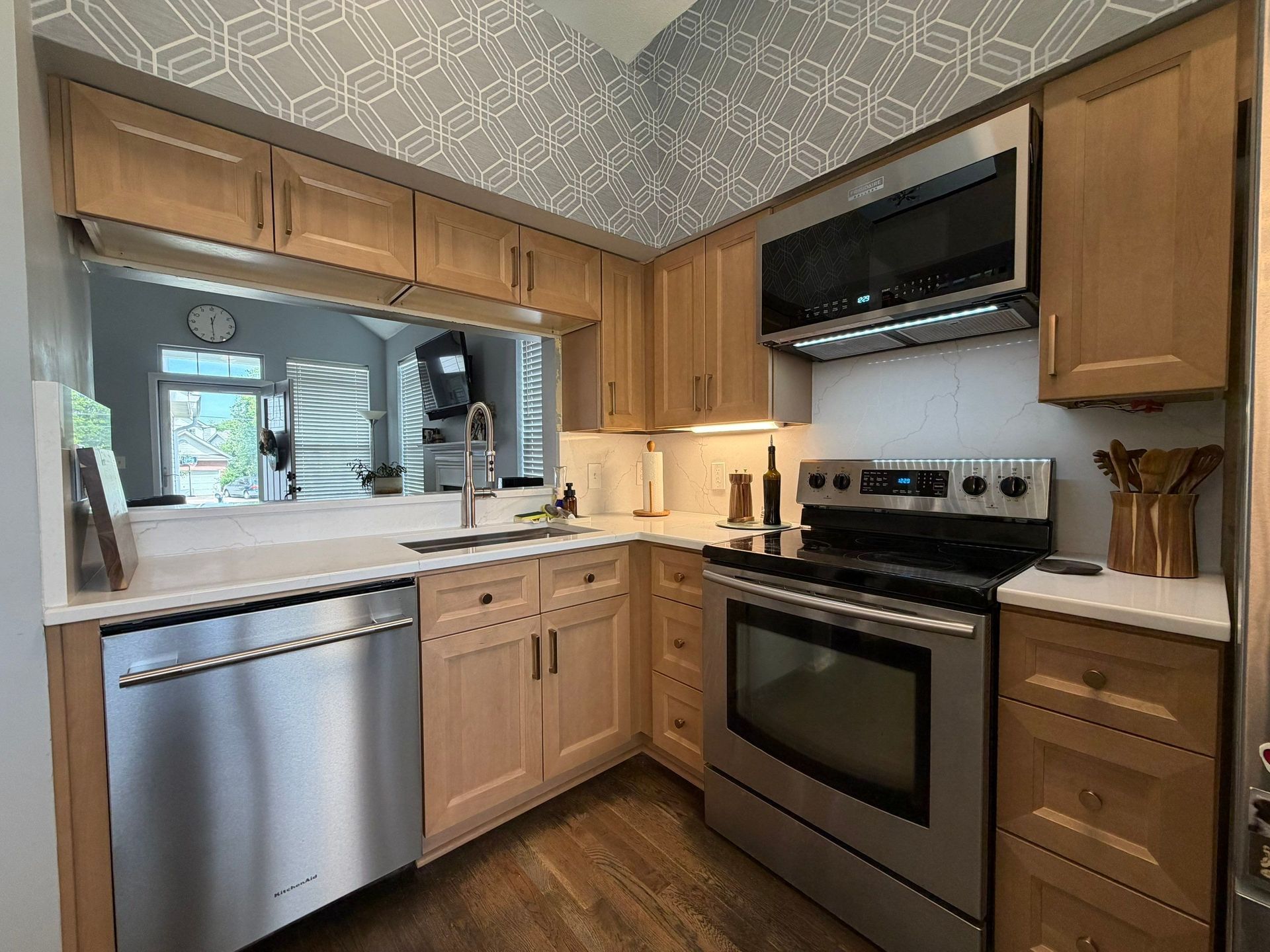 Modern kitchen with stainless steel appliances, wood cabinets, and white countertops
