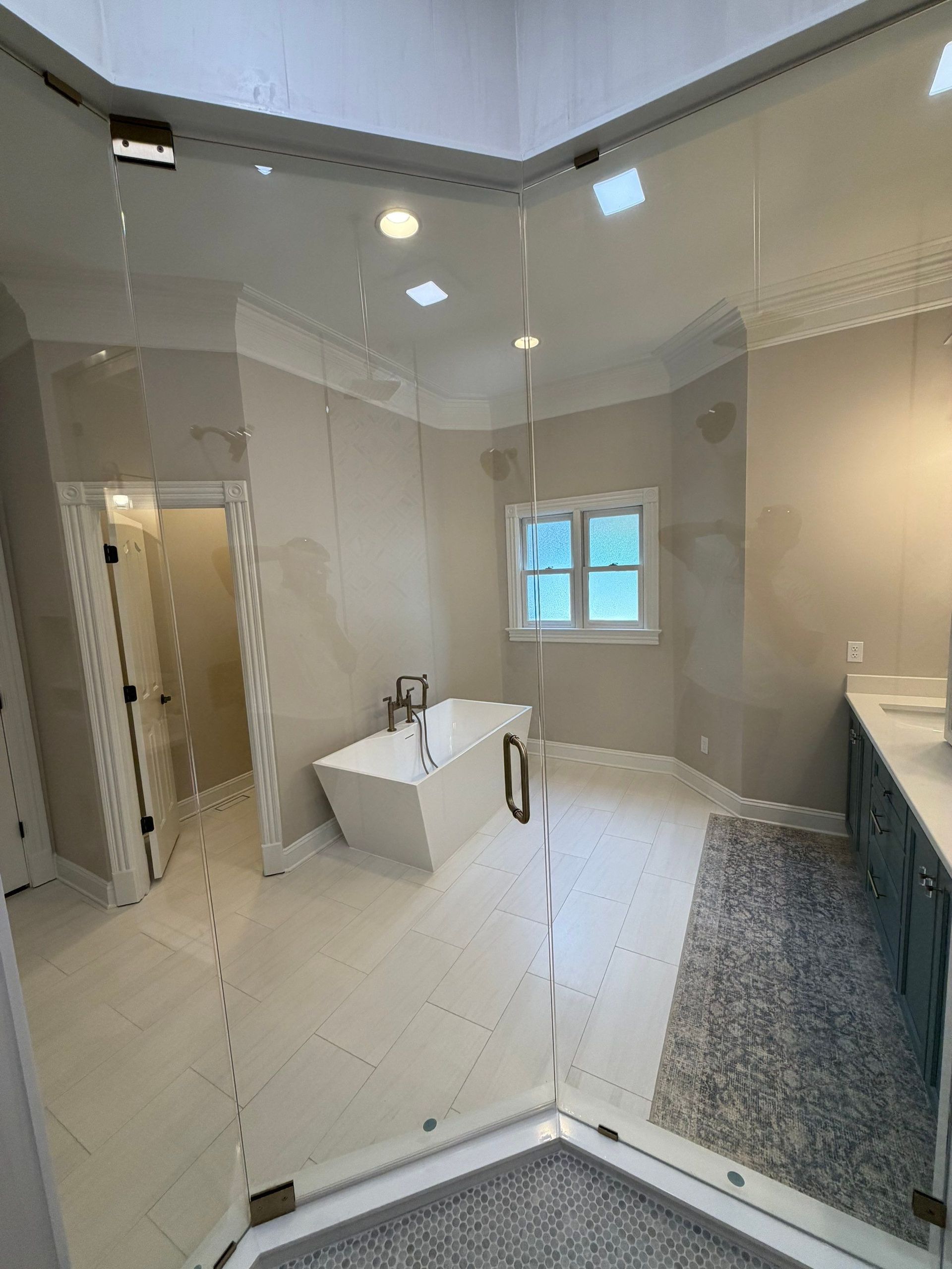 Bathroom transformation features glass shower enclosure, freestanding tub, new tile, and custom lighting in Franklin, TN