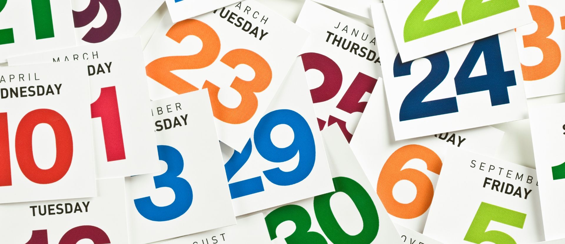 A scattered collection of colorful calendar pages showing various dates, months, and days of the week.