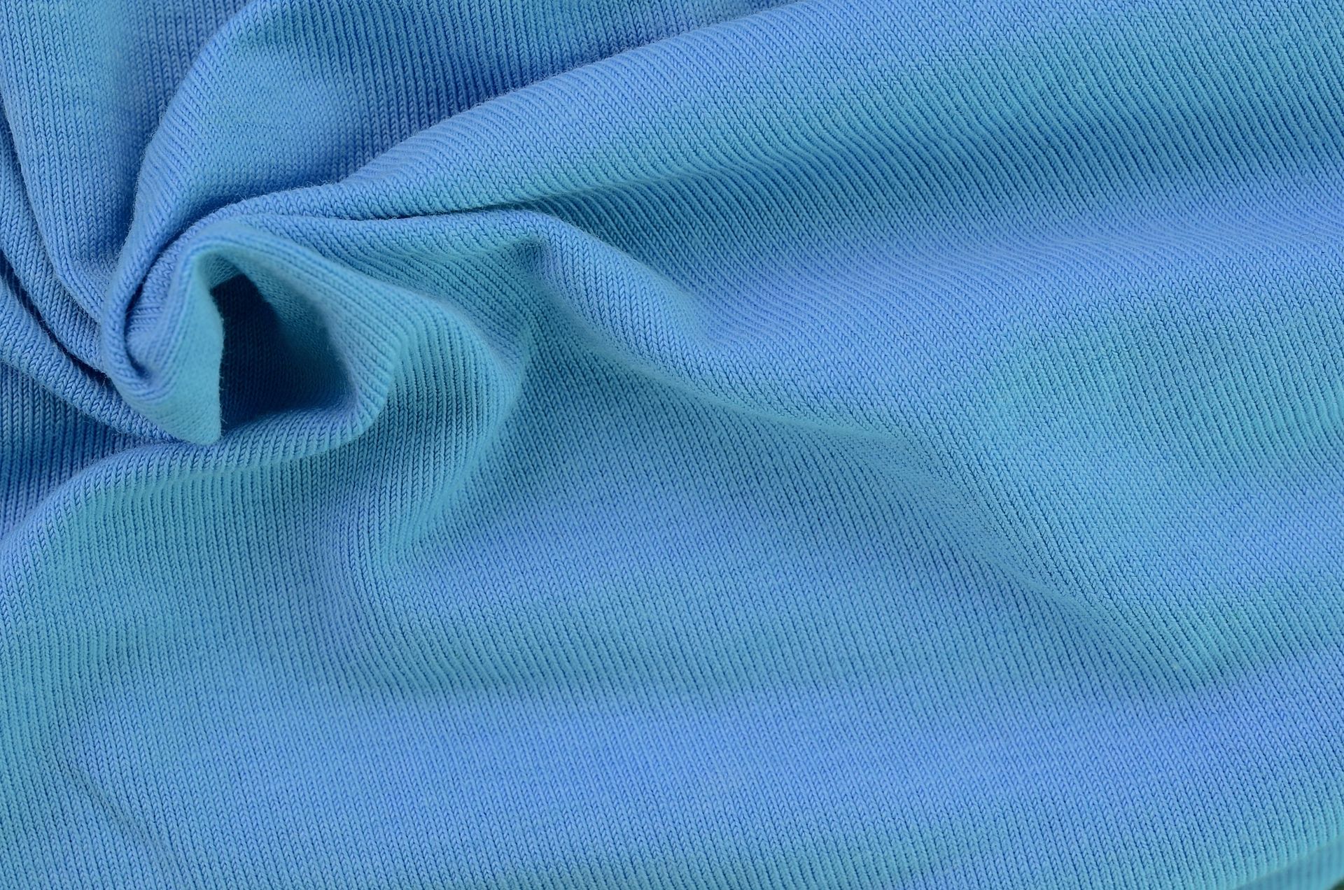 Tessuto lavorato a maglia blu dalla trama sottile, drappeggiato e piegato.