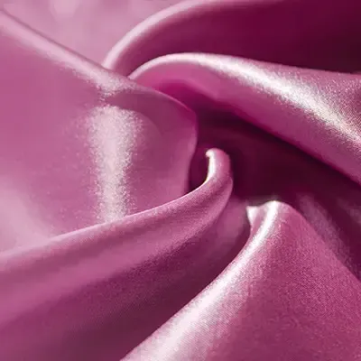 Primo piano di tessuto satinato rosa lucido e ondulato.