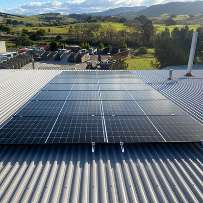 Two Men Are Working On A Solar Panel On Top Of A Building — Solarblu Pty Ltd In Woonona, NSW